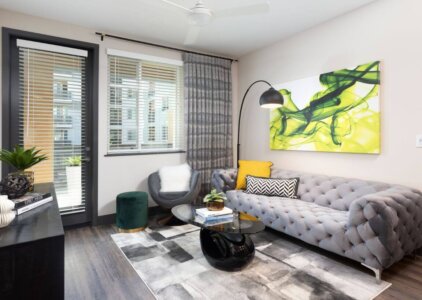 Apartments Anaheim - Rise - Modern Living Room with Stylish Furniture, Art Hanging on the Walls, Hardwood Style Flooring, and a Door Leading to a Balcony